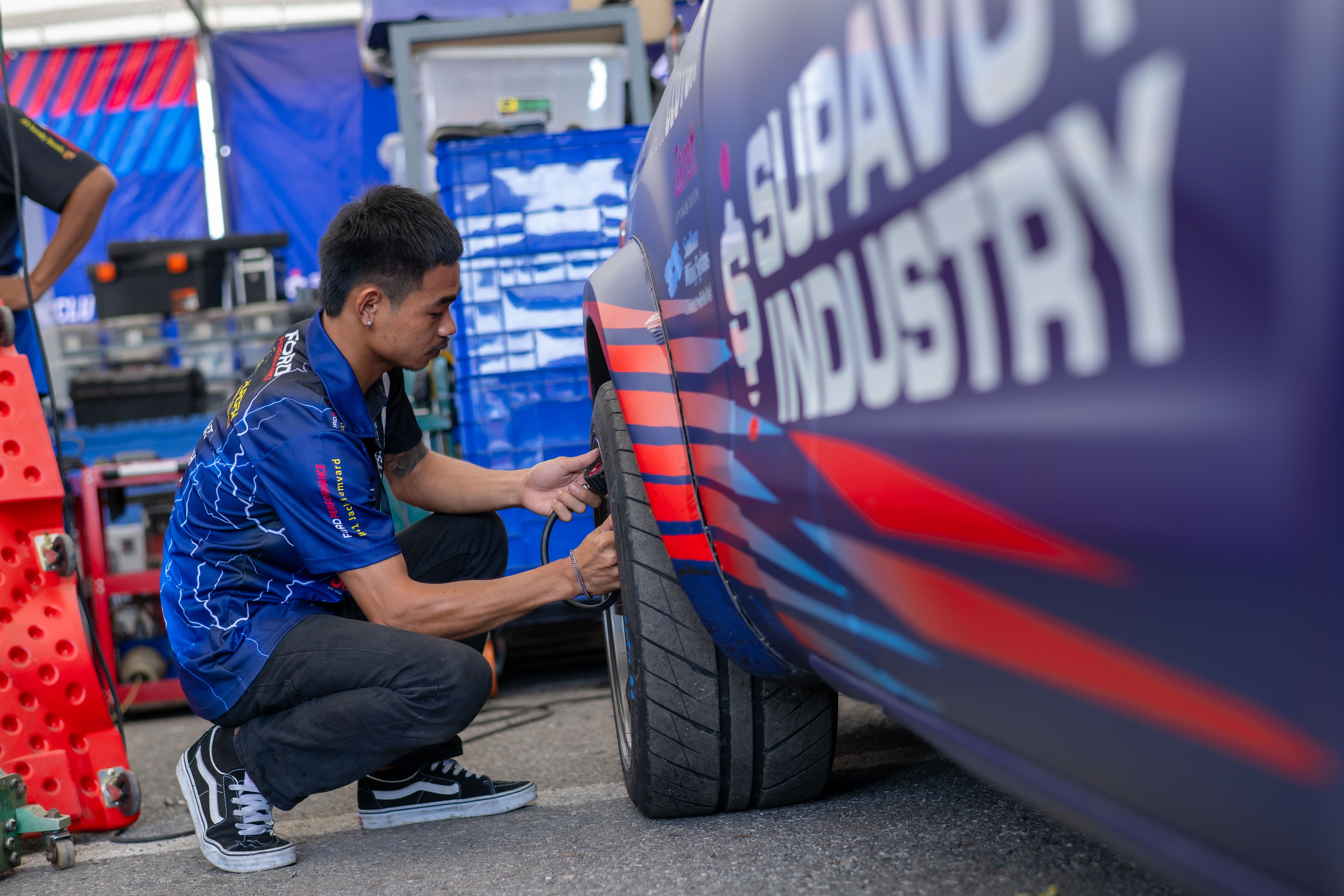 A Ford Thailand Racing crew member checking the tire pressure on a Hankook racing slick tire. 